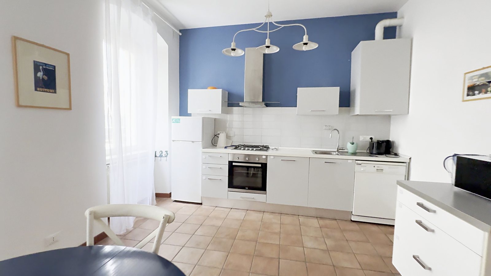 Küche mit blauer Wand, Backofen, Gaskochfeld und weißer Insel, Wohnung in der Via Machiavelli, Triest