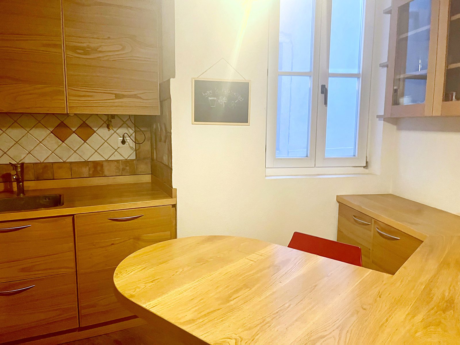 Cucina con tavolo a penisola in legno, finestra e lavagnetta appesa, via dei Capitelli, Trieste