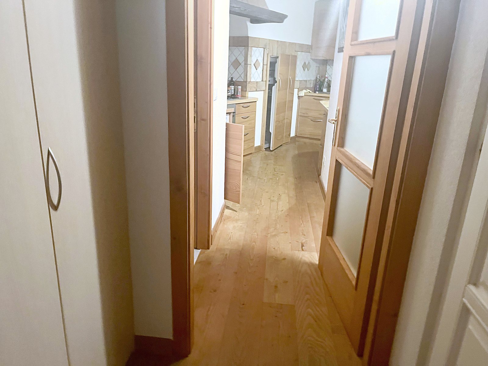 Disimpegno con armadio alto bianco e porta a vetri verso la cucina, via dei Capitelli, Trieste