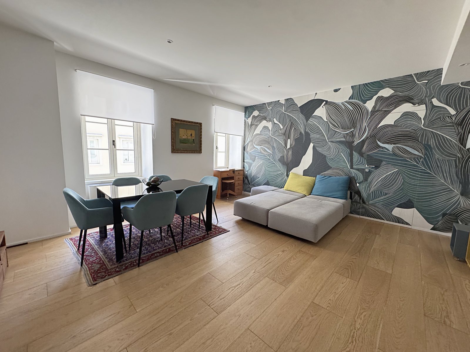 Living room with large-leaf wallpaper, grey sofa and table with green chairs, Via San Nicolò, Trieste