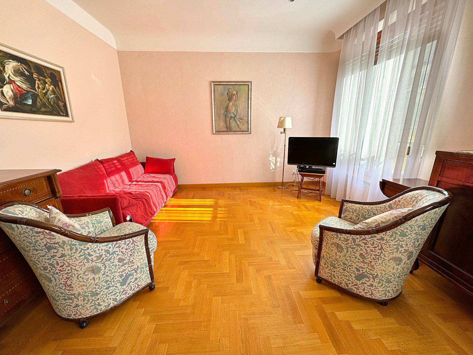 Sitting area with red sofa, two floral armchairs and paintings on the walls, Via San Francesco d'Assisi, Trieste