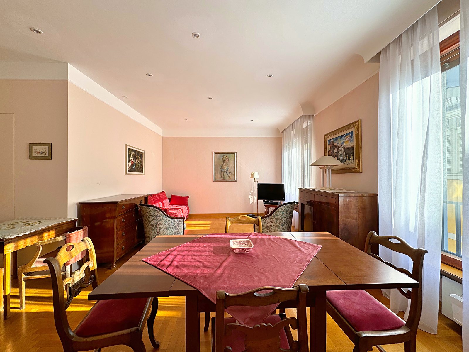 Extending dining table, red sofa and bright windows in the fourth-floor living room, Via San Francesco d'Assisi, Trieste