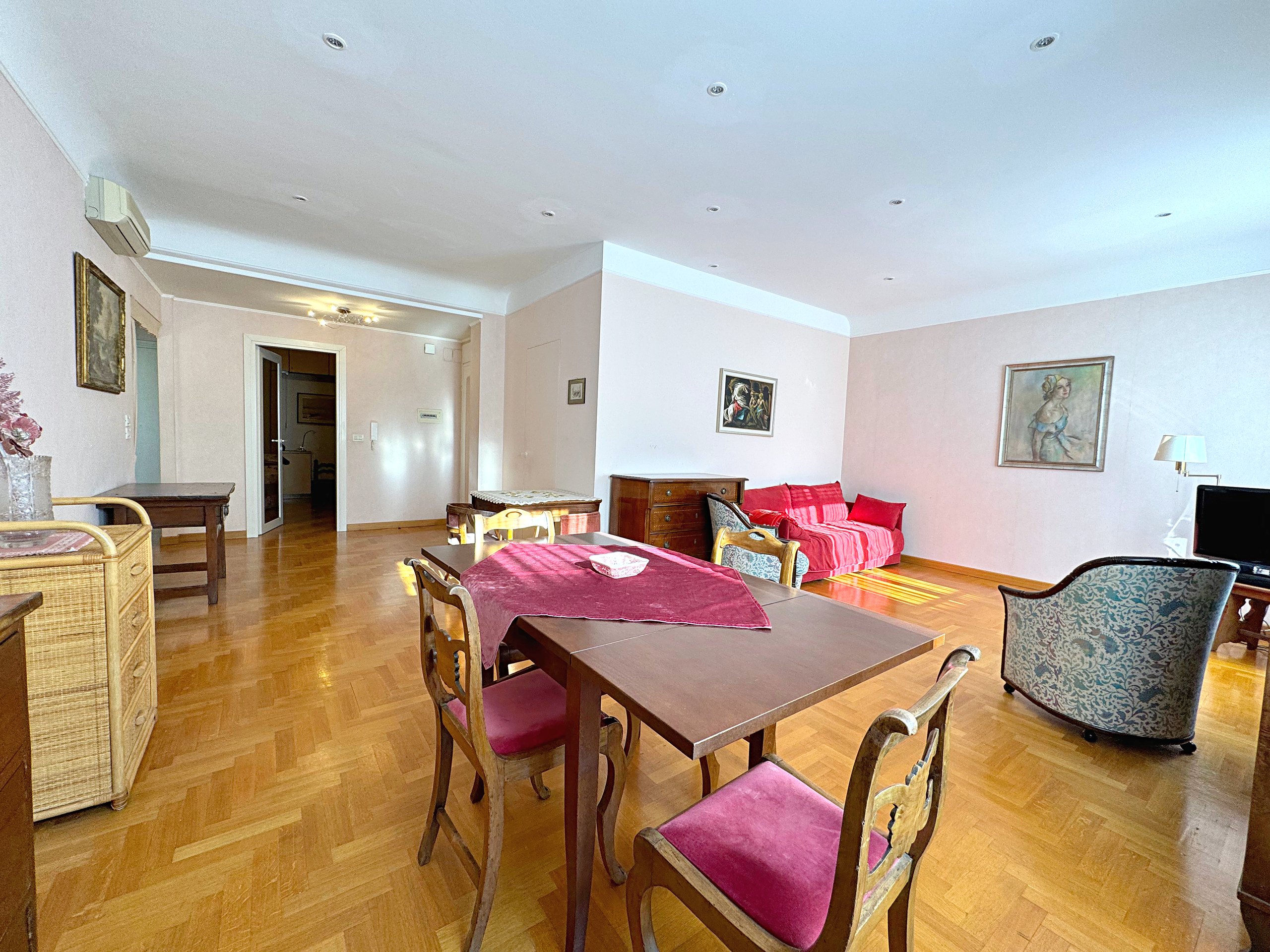 Living room with dining area, herringbone parquet and red sofa, flat in Via San Francesco d'Assisi, Trieste