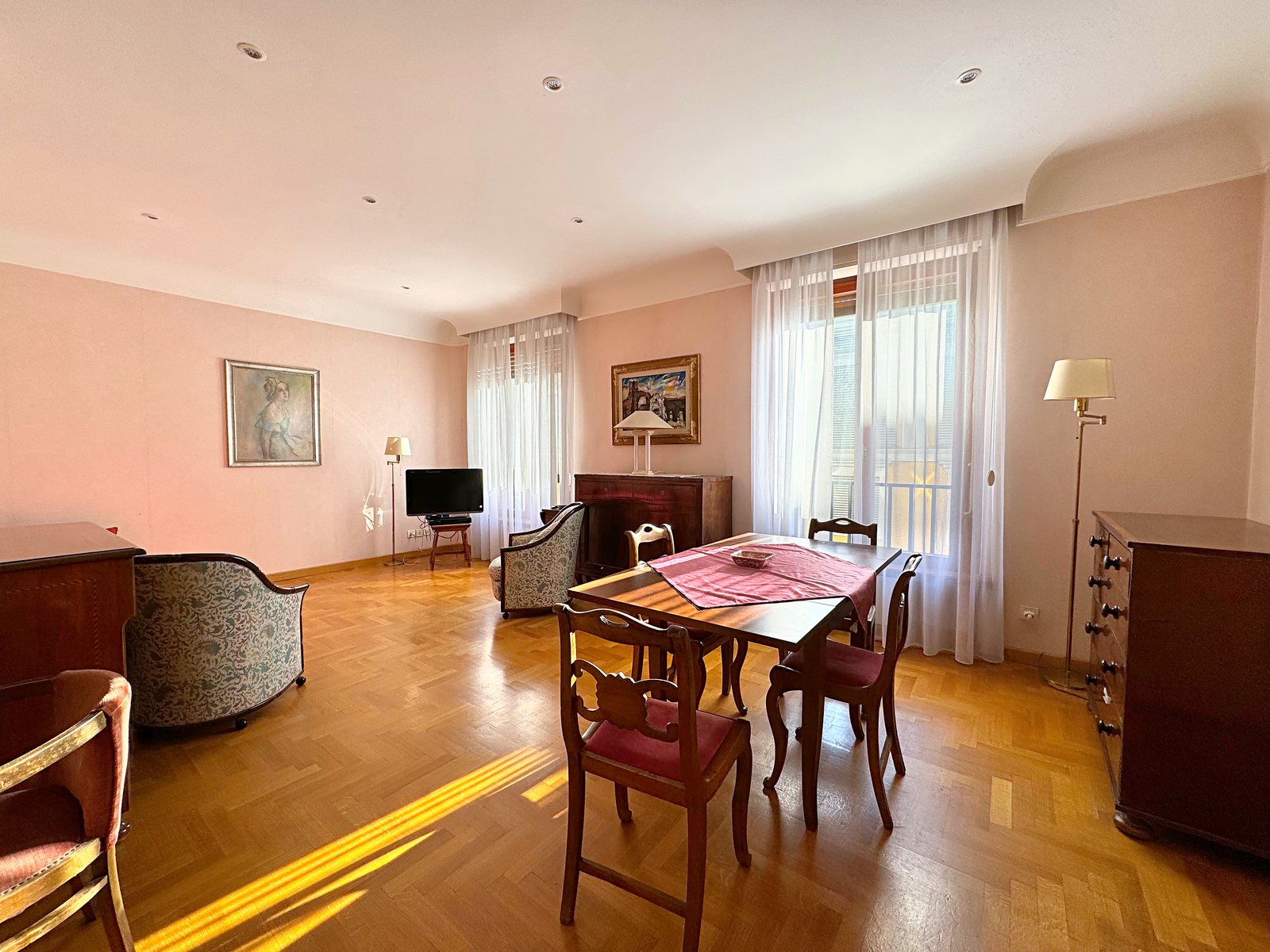 Dining area of the living room with wooden table and French windows with light curtains, Via San Francesco d'Assisi, Trieste