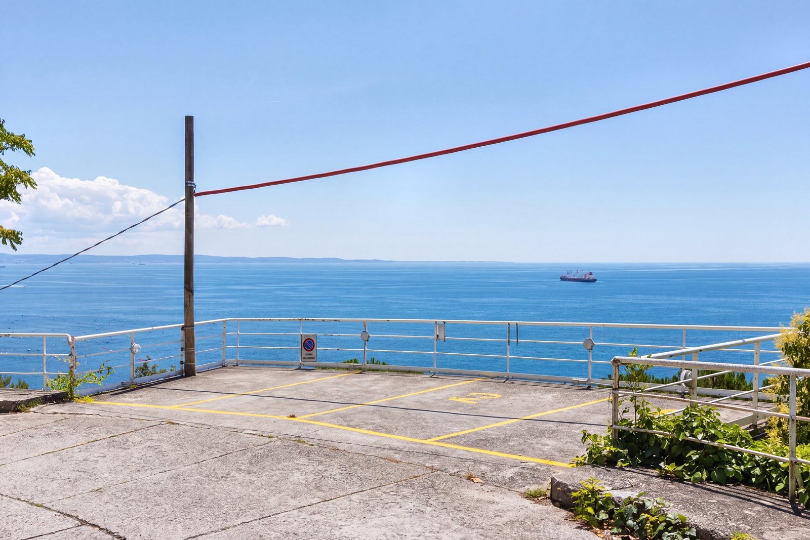 Private parking platform with yellow-marked spaces, overlooking the Gulf of Trieste