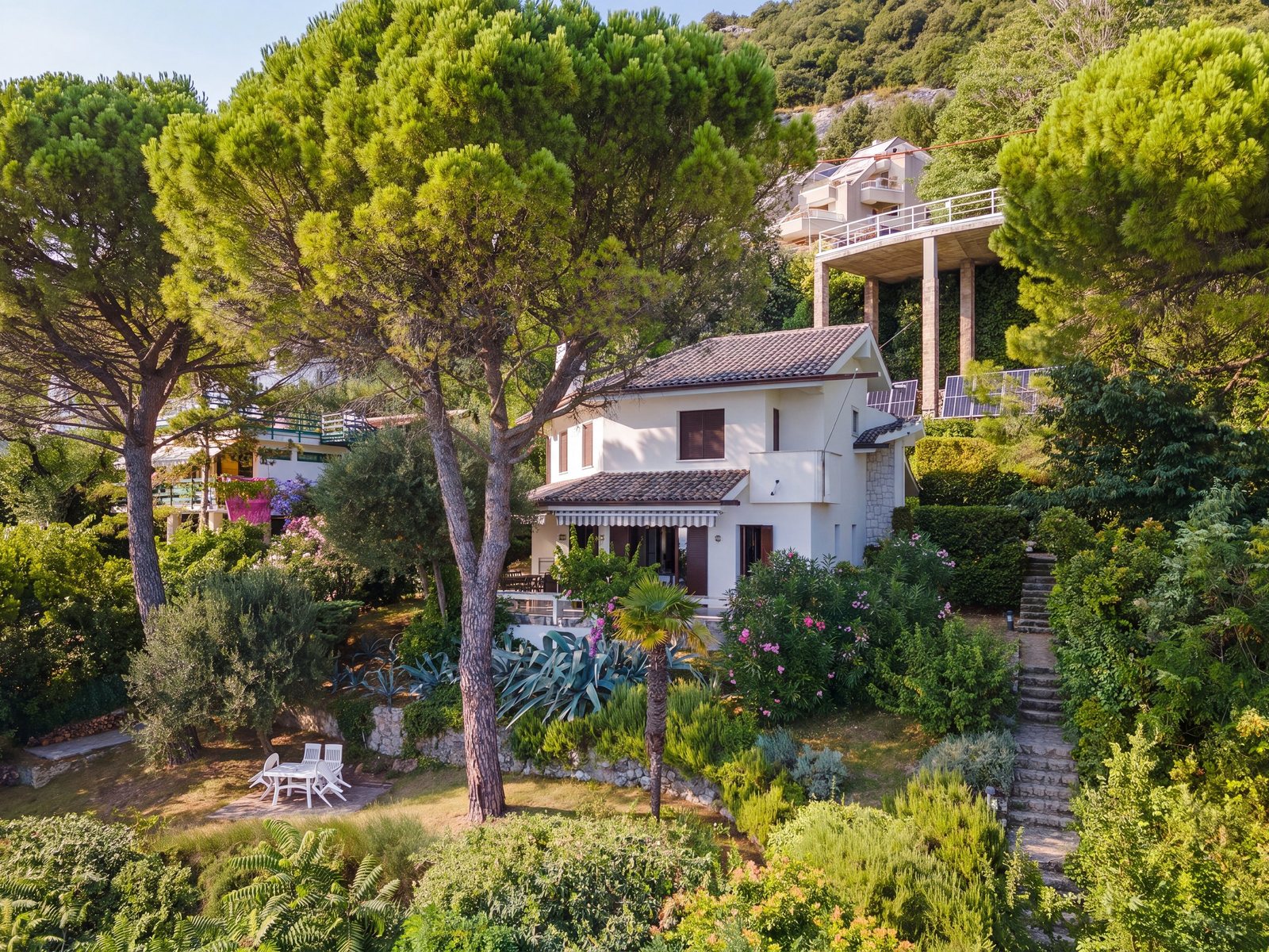 The villa from above among the pines, with the parking platform and the garden steps