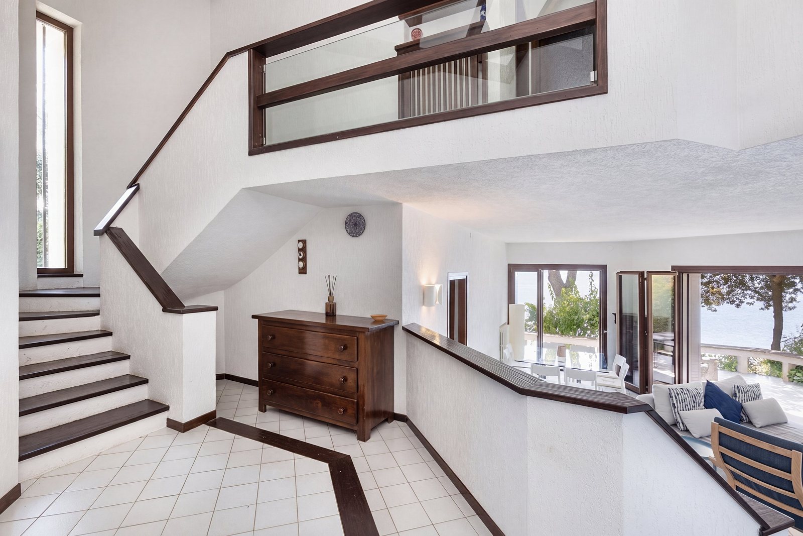 Entrance hall with wooden staircase, chest of drawers and view into the living room