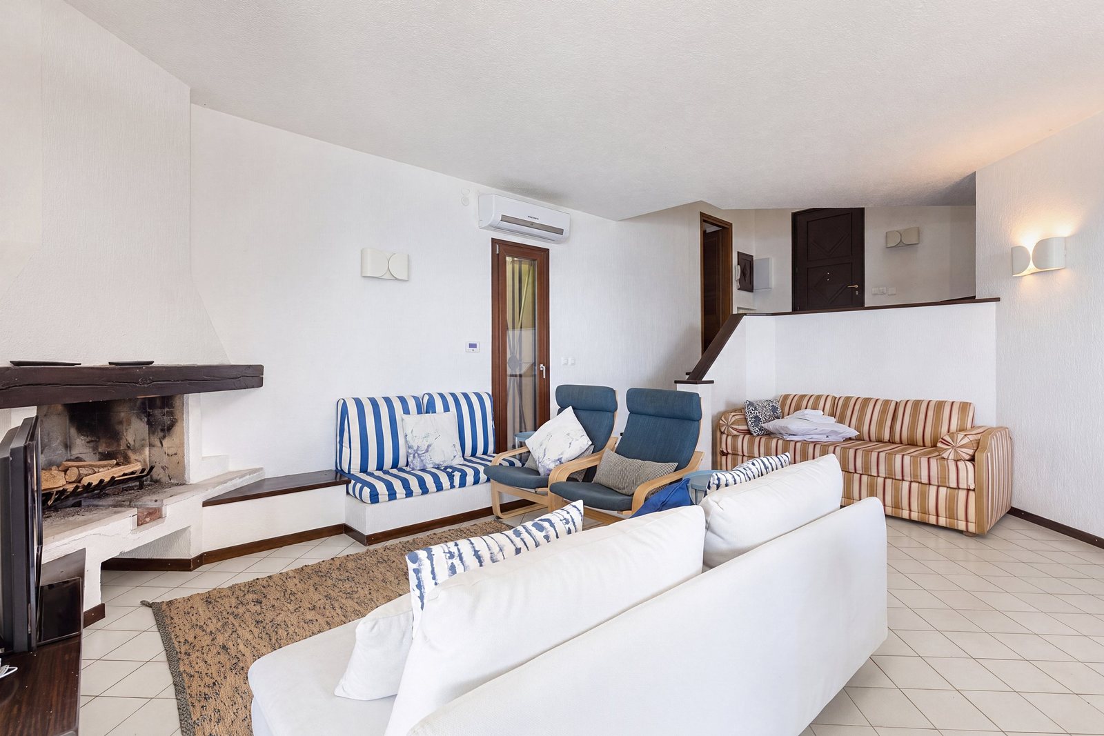 Living room with fireplace, white sofa, blue-striped sofa and armchairs