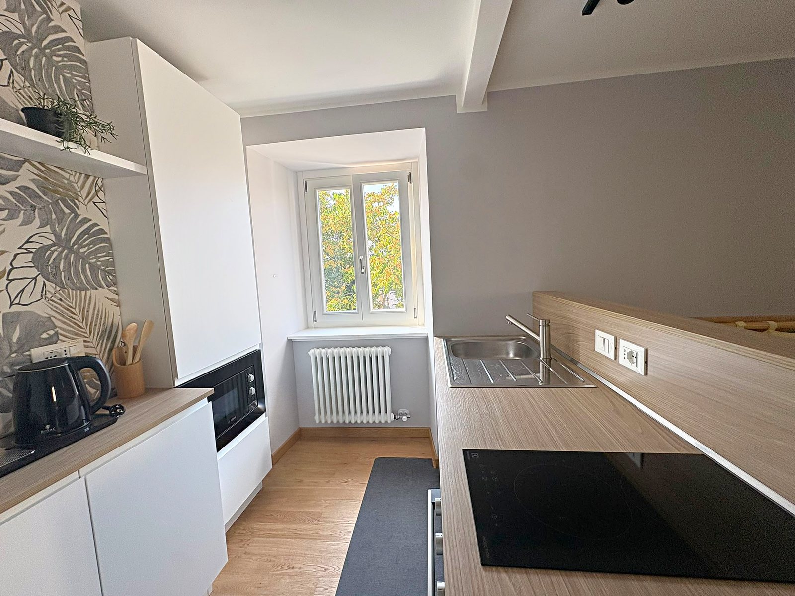 Cucina con lavello in acciaio, piano a induzione e finestra sugli alberi, via dei Battaglia, Trieste