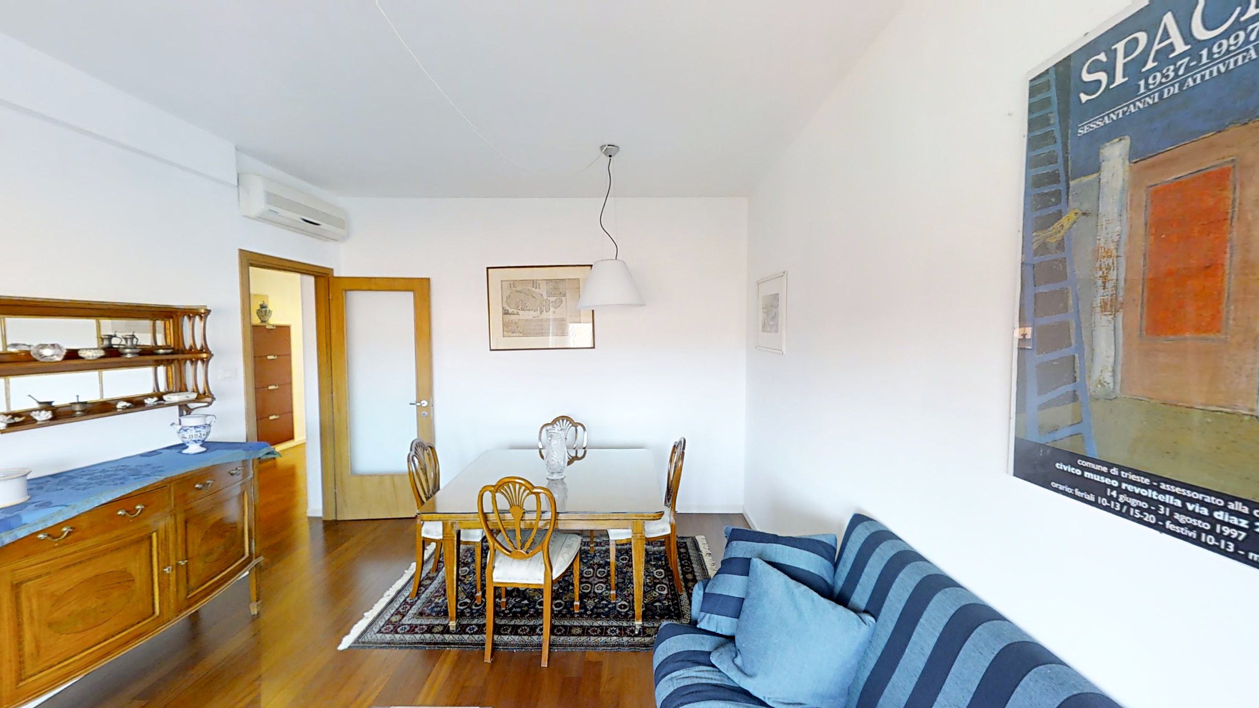 Wohnzimmer mit Esstisch, geschnitzten Stühlen und blau gestreiftem Sofa, Via Slataper, Triest