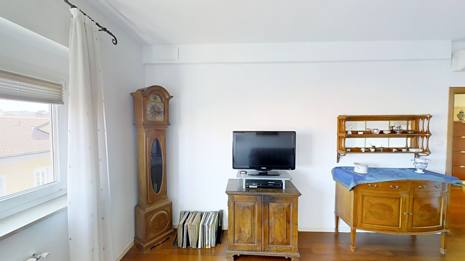 Wohnzimmer mit Standuhr, antiker Anrichte und Fenster über den Dächern, Via Slataper, Triest