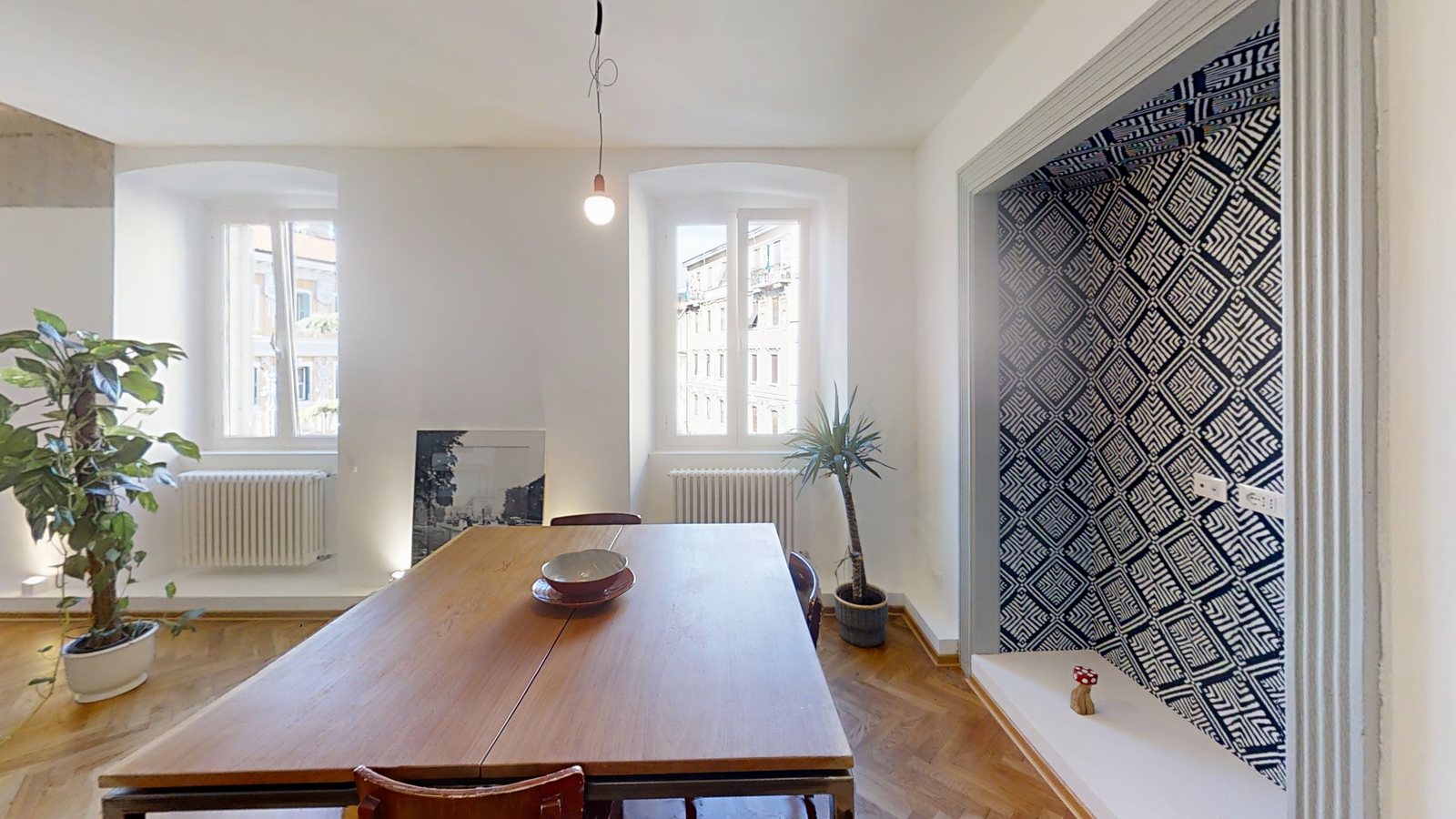 Essbereich mit langem Holztisch, zwei Fenstern und Nische mit blau-weißer Tapete, Via dei Fabbri, Triest