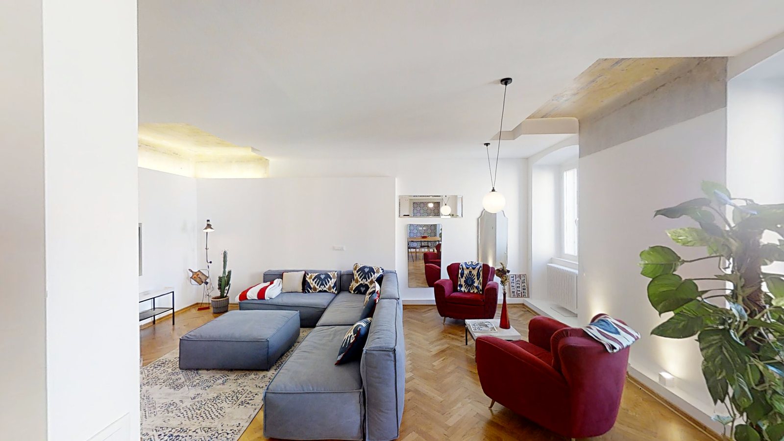 Offener Wohnbereich mit grauem Ecksofa, roten Sesseln und altem Putz in der Decke, Via dei Fabbri, Triest