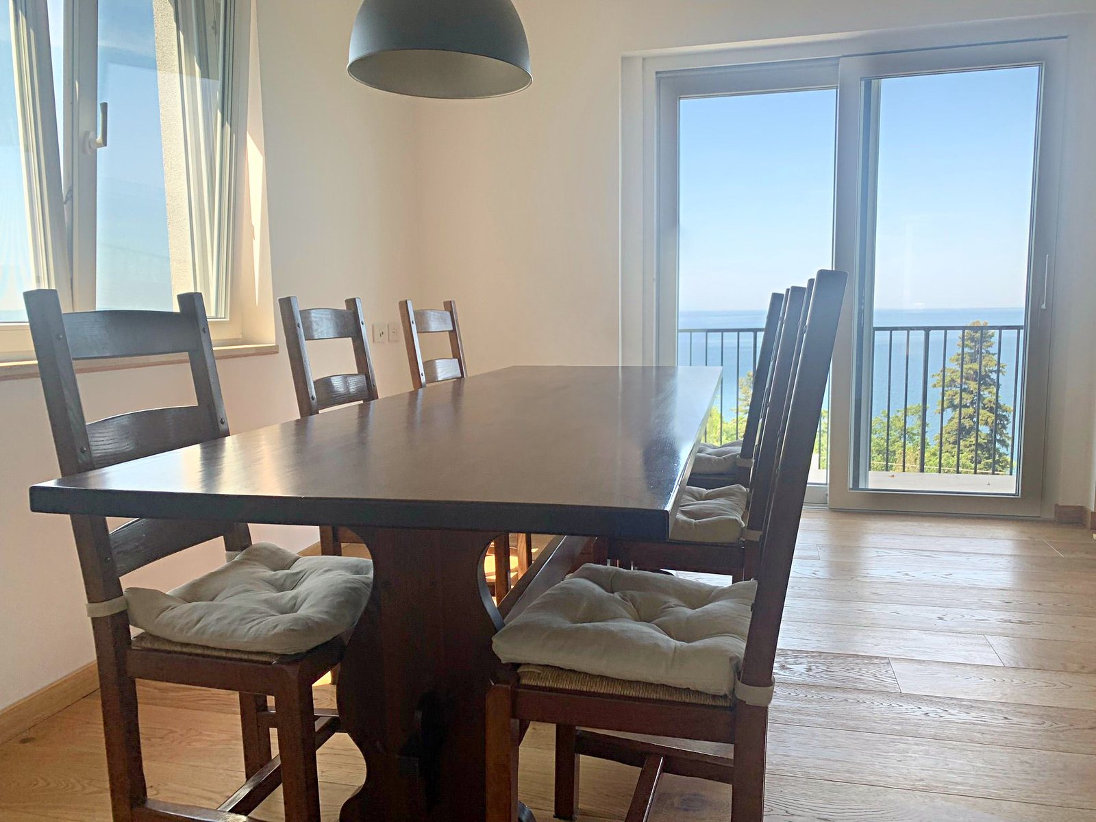 Dark wooden dining table in front of the French window with sea view, Salita di Cedassamare, Trieste