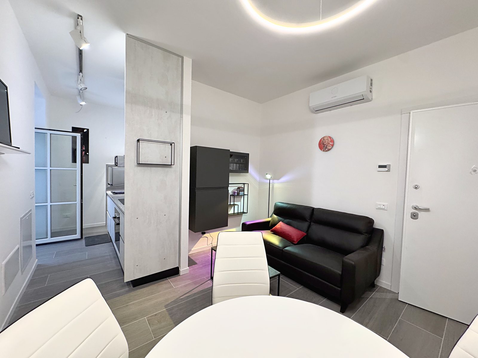 Living room with black leather sofa, air conditioning and access to the kitchen, flat in Via del Lavatoio, Trieste