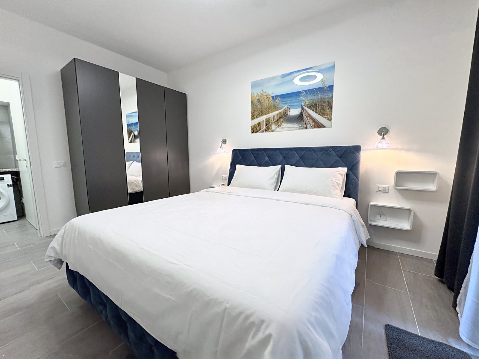 Double bedroom with mirrored wardrobe and doorway to the laundry room, flat in Via del Lavatoio, Trieste