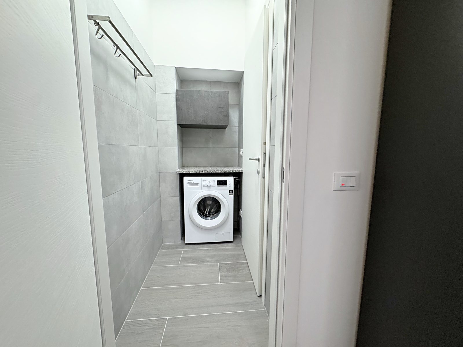 Laundry room with washing machine, granite shelf and wall cabinet, flat in Via del Lavatoio, Trieste