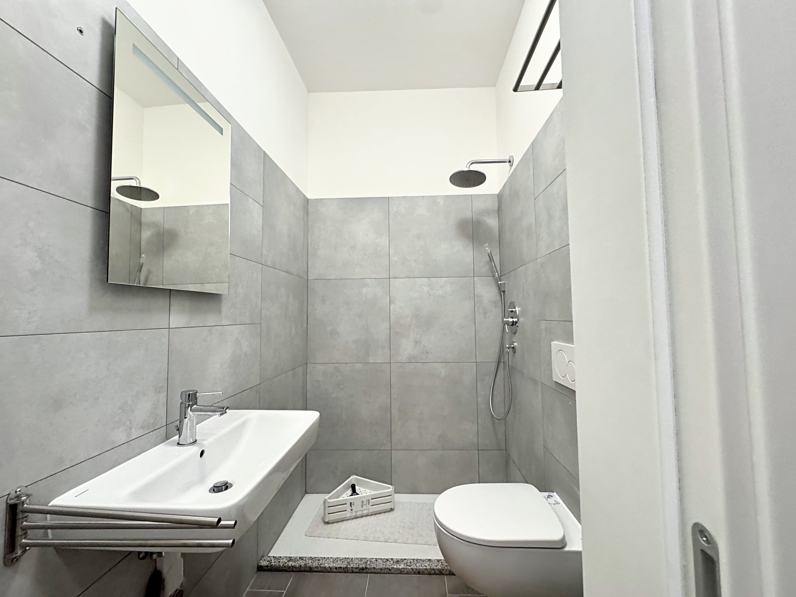 Bathroom with shower behind a granite threshold, wall-hung fixtures and grey tiles, Via del Lavatoio, Trieste