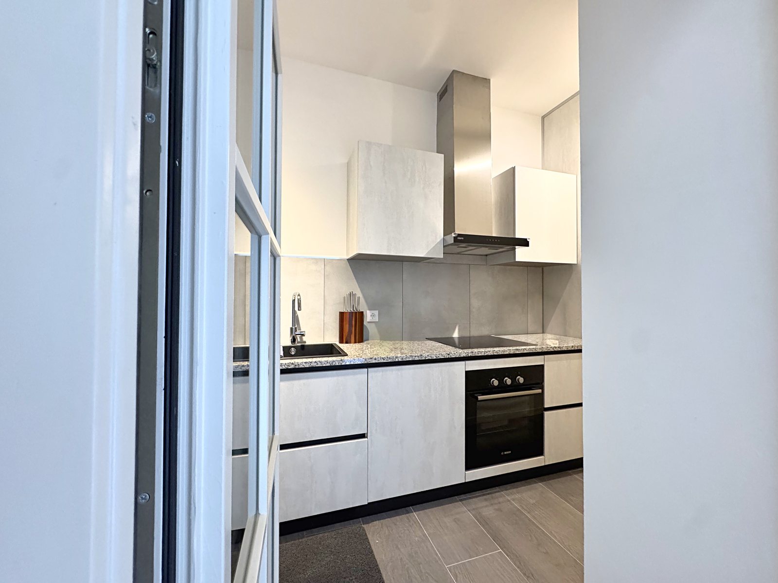 Kitchen seen from the small terrace, with built-in oven, steel hood and granite worktop, Via del Lavatoio, Trieste