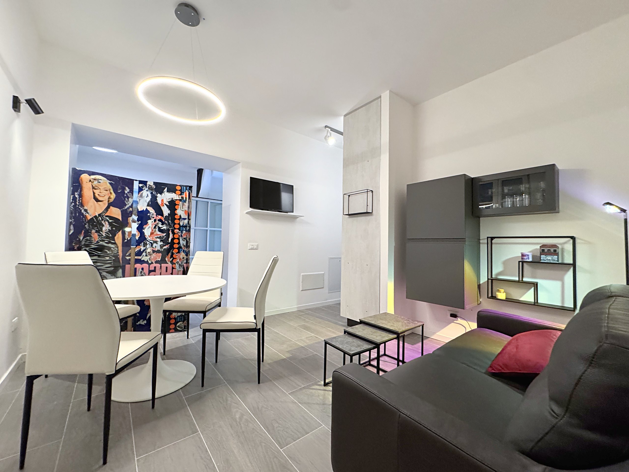 Living area with round table, black leather sofa and pop-art folding screen, flat in Via del Lavatoio, Trieste