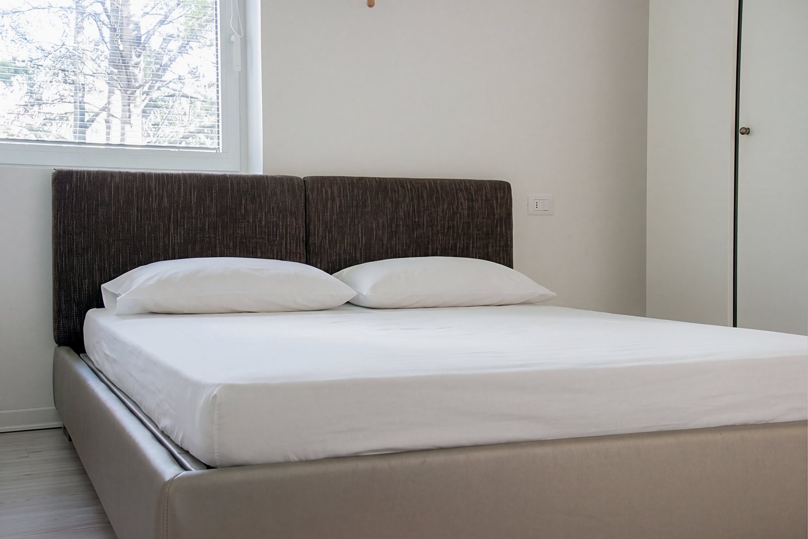 Spalnica z zakonsko posteljo, oblazinjenim vzglavjem in oknom na drevesa, Largo Promontorio, Trst