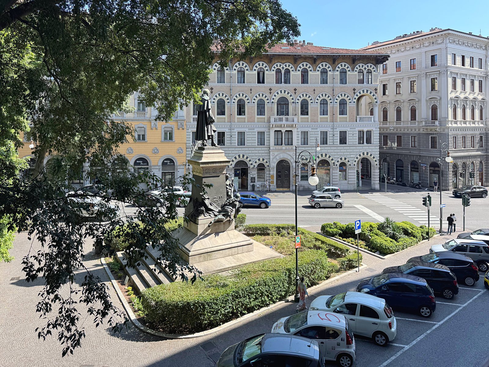 Vista dalla finestra sul monumento, sulle aiuole e sui palazzi storici di fronte, via Marconi, Trieste