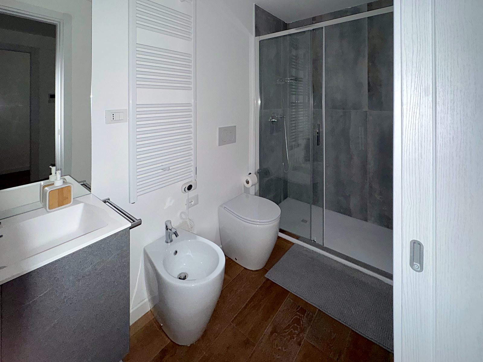 Bagno con scaldasalviette, sanitari bianchi e doccia grande in cristallo, via Marconi, Trieste
