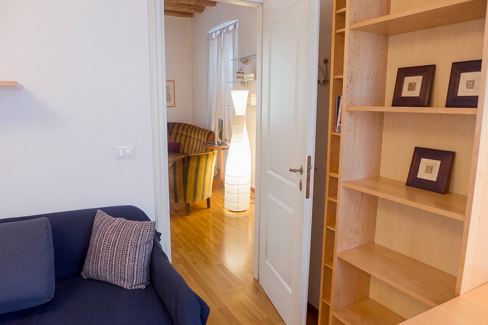 Arbeitszimmer mit hellem Holzregal und Blick in den Nebenraum mit Sesseln, Viale della Terza Armata, Triest