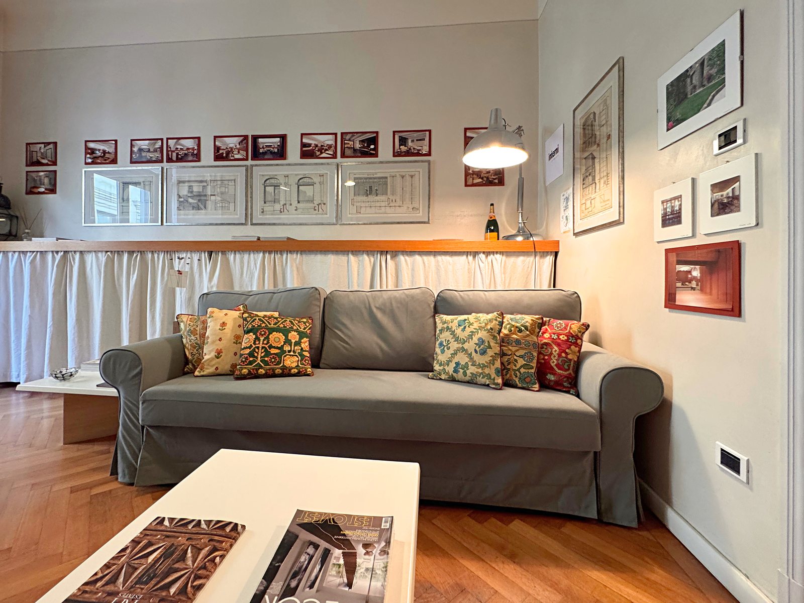 Sitting room with grey sofa and architectural drawings on the walls, Via Santa Caterina, Trieste