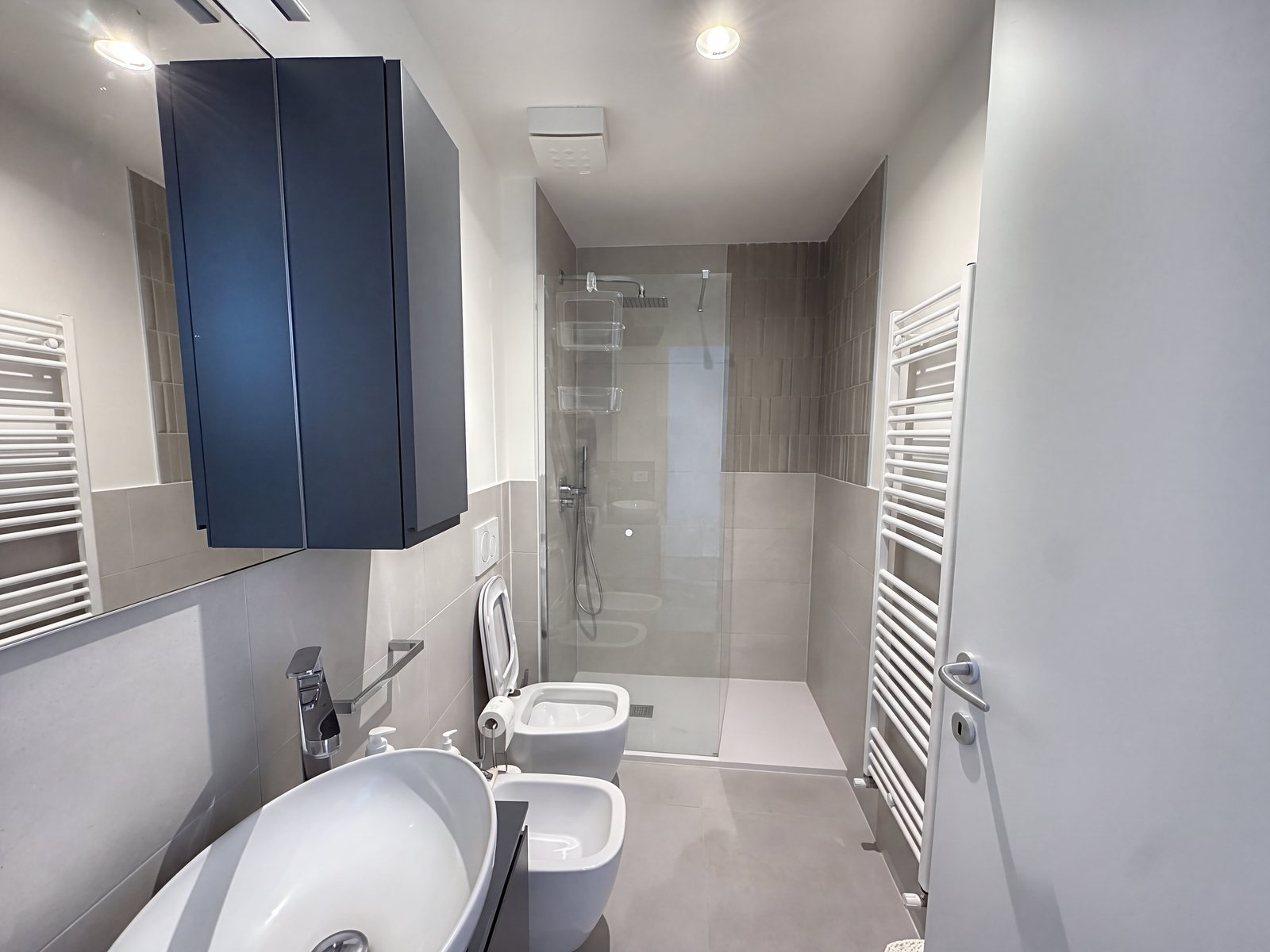 Bathroom with countertop basin, blue wall cabinet, wall-hung fittings and glass shower, Salita di Gretta, Trieste