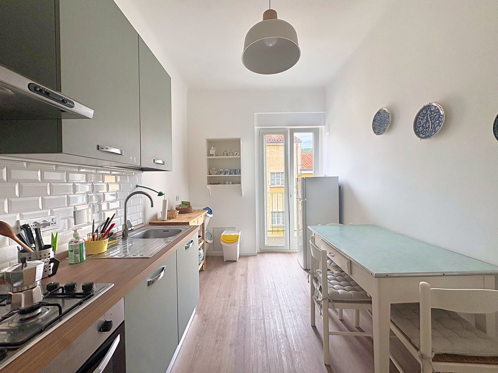Cucina abitabile con tavolo, mobili verde salvia e porta-finestra sul balcone del cortile, viale XX Settembre, Trieste