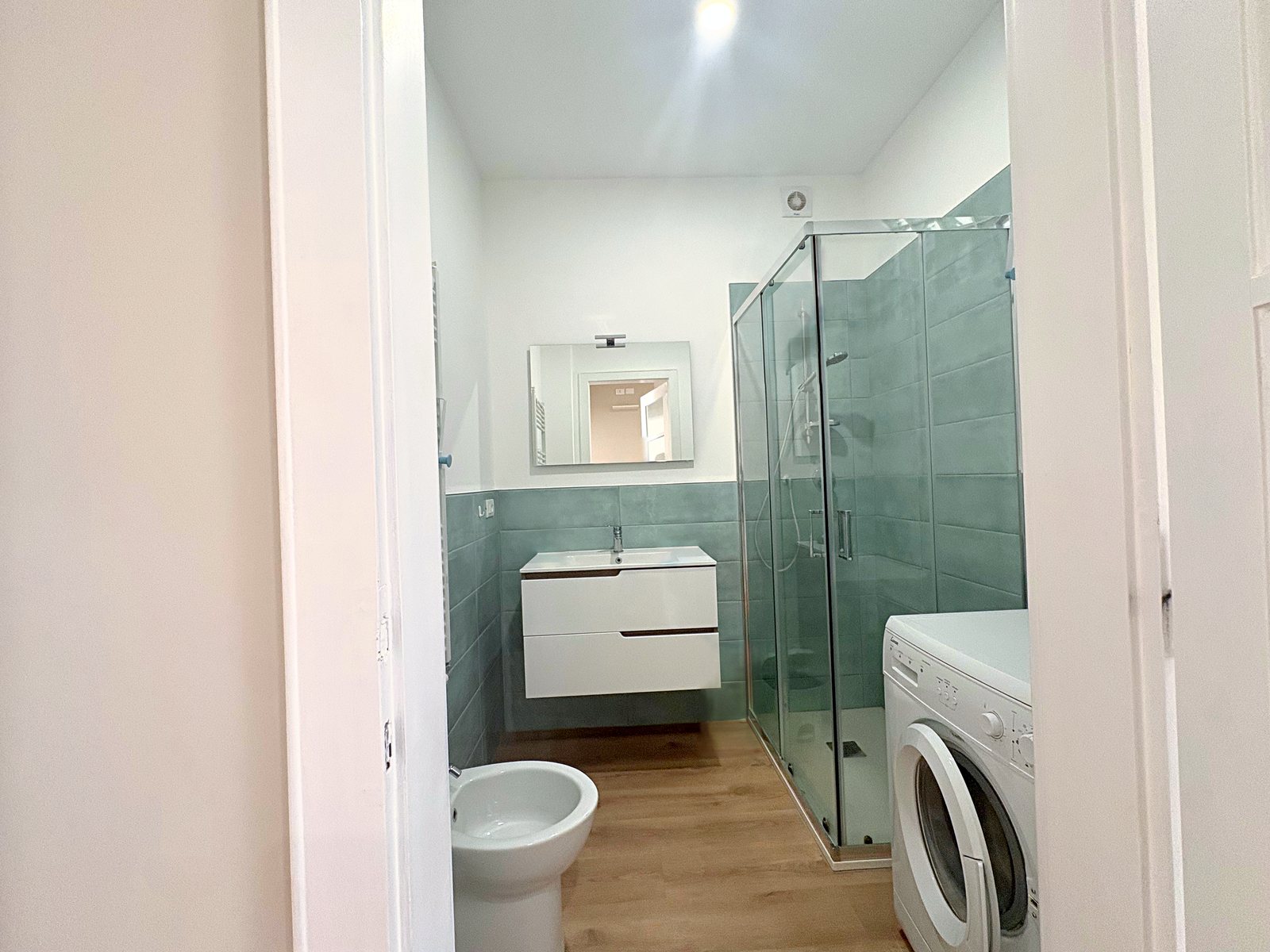 Bagno con doccia in cristallo, piastrelle verde acqua, lavabo sospeso, bidet e lavatrice, viale XX Settembre, Trieste