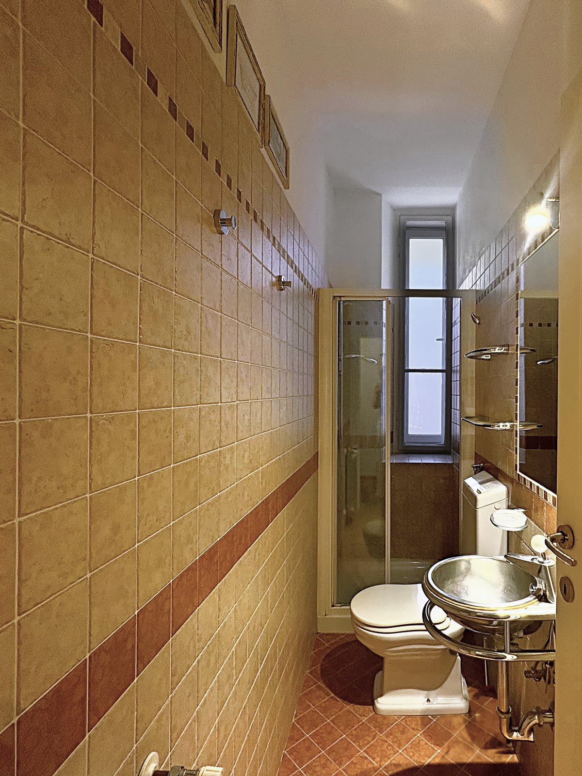 Secondo bagno con doccia, lavabo in acciaio e piastrelle beige con fascia in cotto, via San Giorgio, Trieste