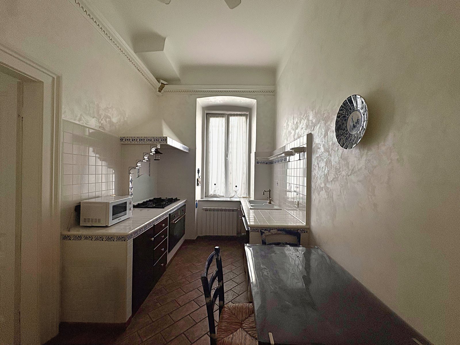 Cucina con piano piastrellato bianco e blu, forno, piano a gas e finestra in fondo, via San Giorgio, Trieste