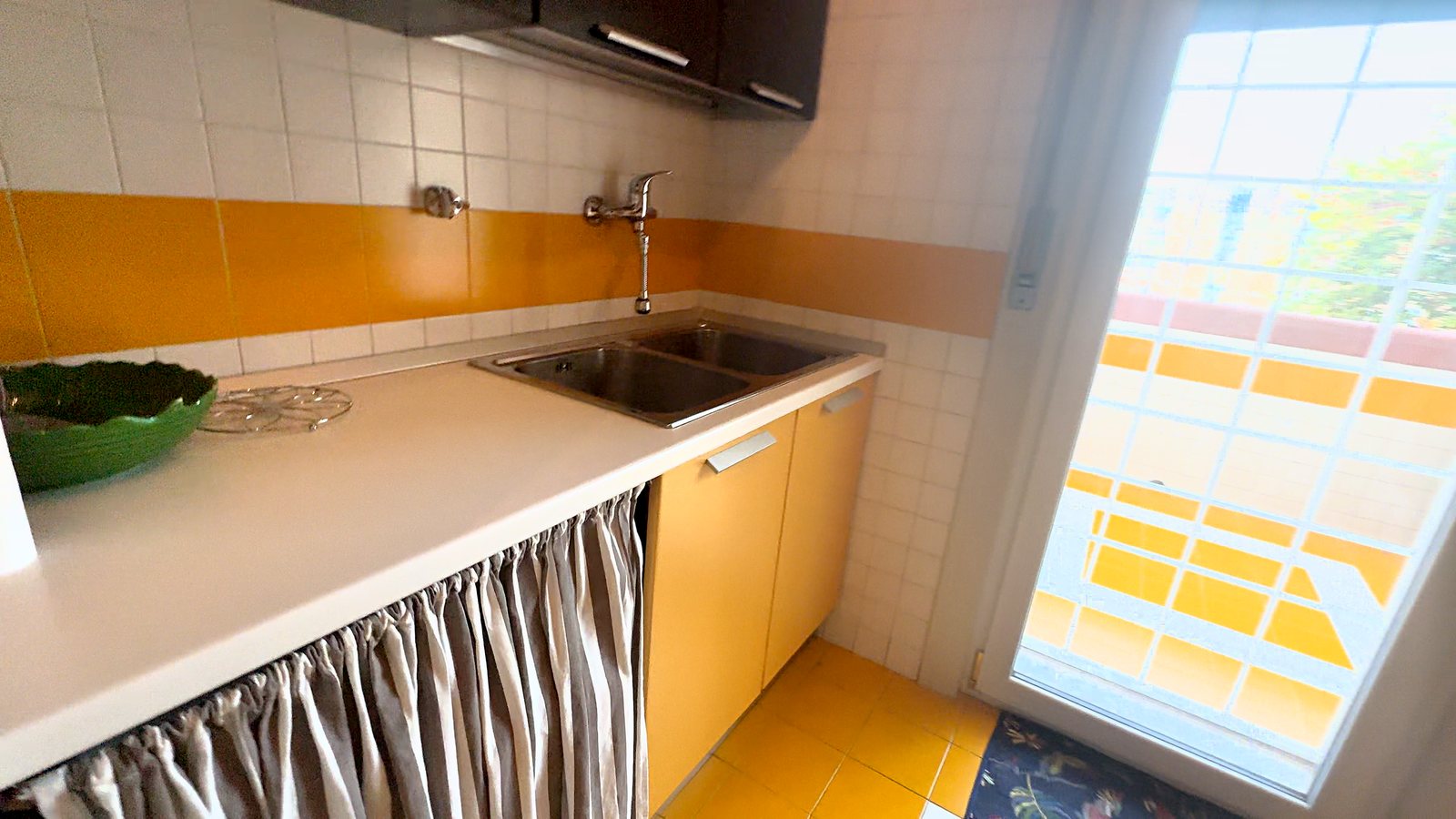 Čajna kuhinja z dvojnim jeklenim koritom, rumenimi ploščicami in vrati na balkon, Via Belpoggio, Trst