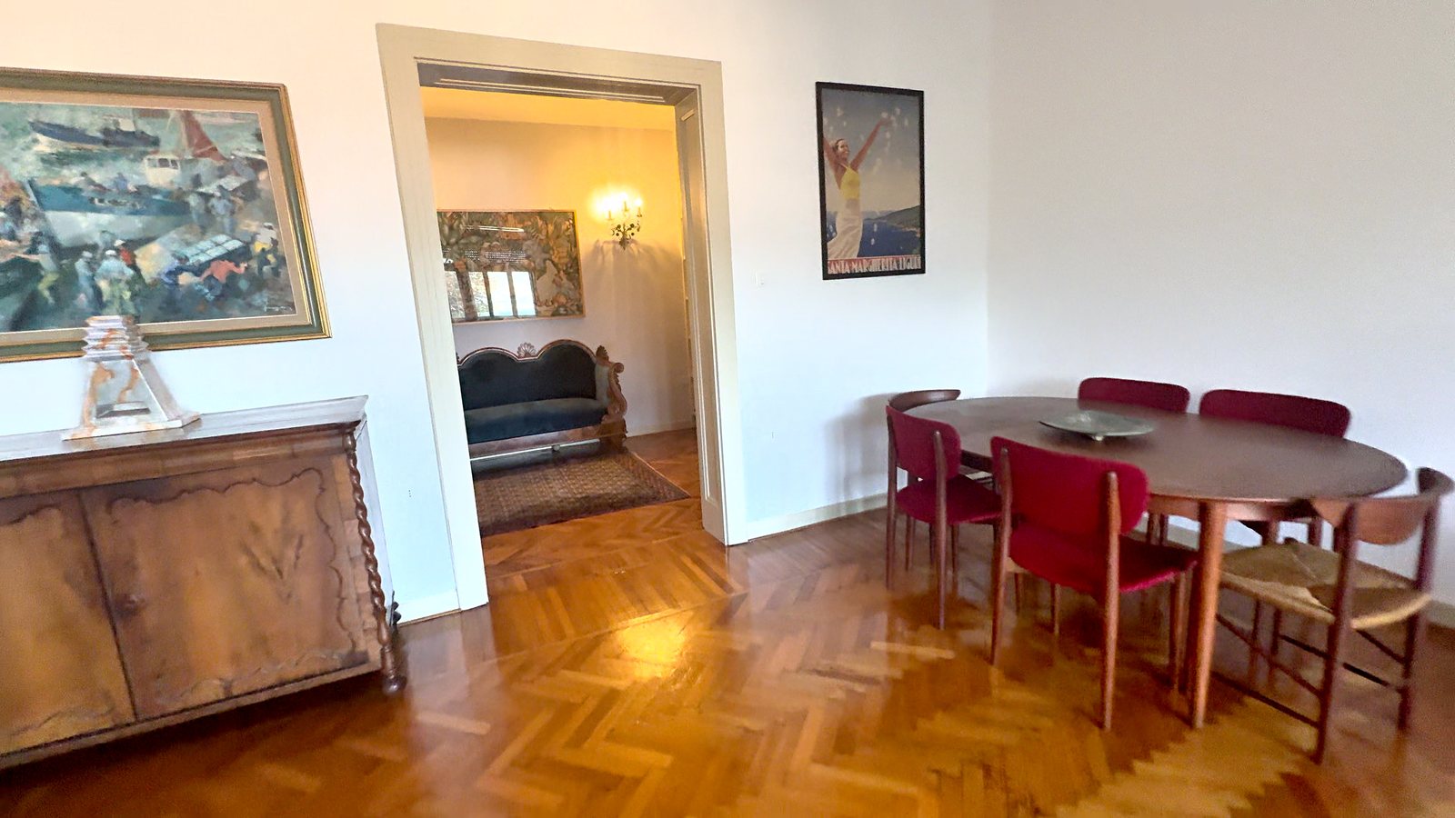 Jedilni del z ovalno leseno mizo, škrlatnimi oblazinjenimi stoli in orehovo komodo, Via Belpoggio, Trst
