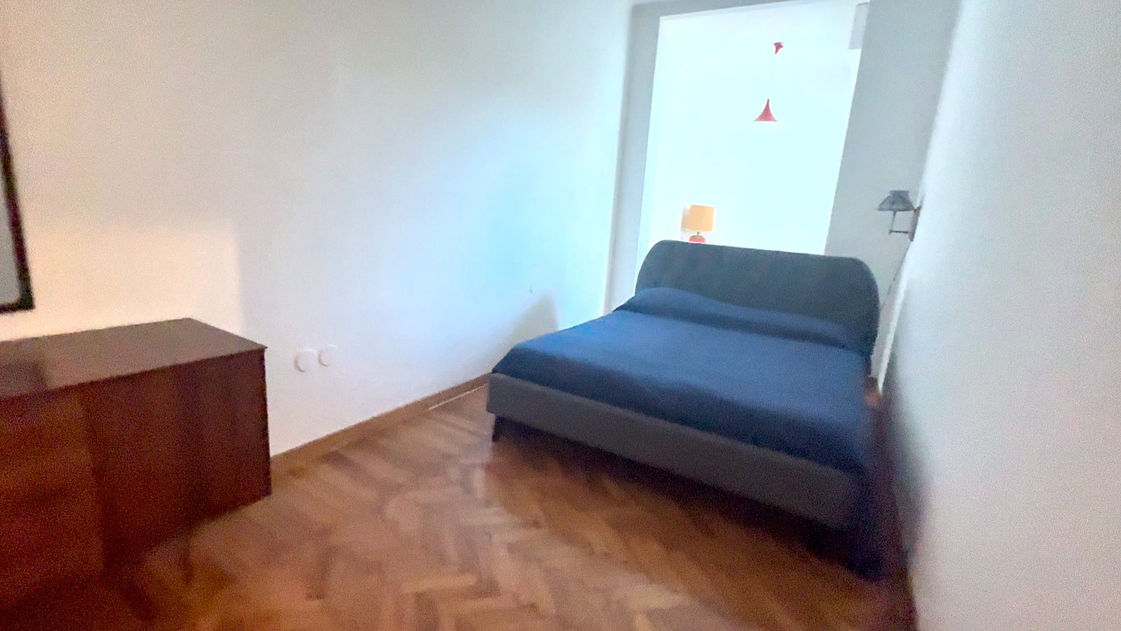 Spalnica z zakonsko posteljo s sivim vzglavjem, modrim pregrinjalom in leseno komodo, Via Belpoggio, Trst