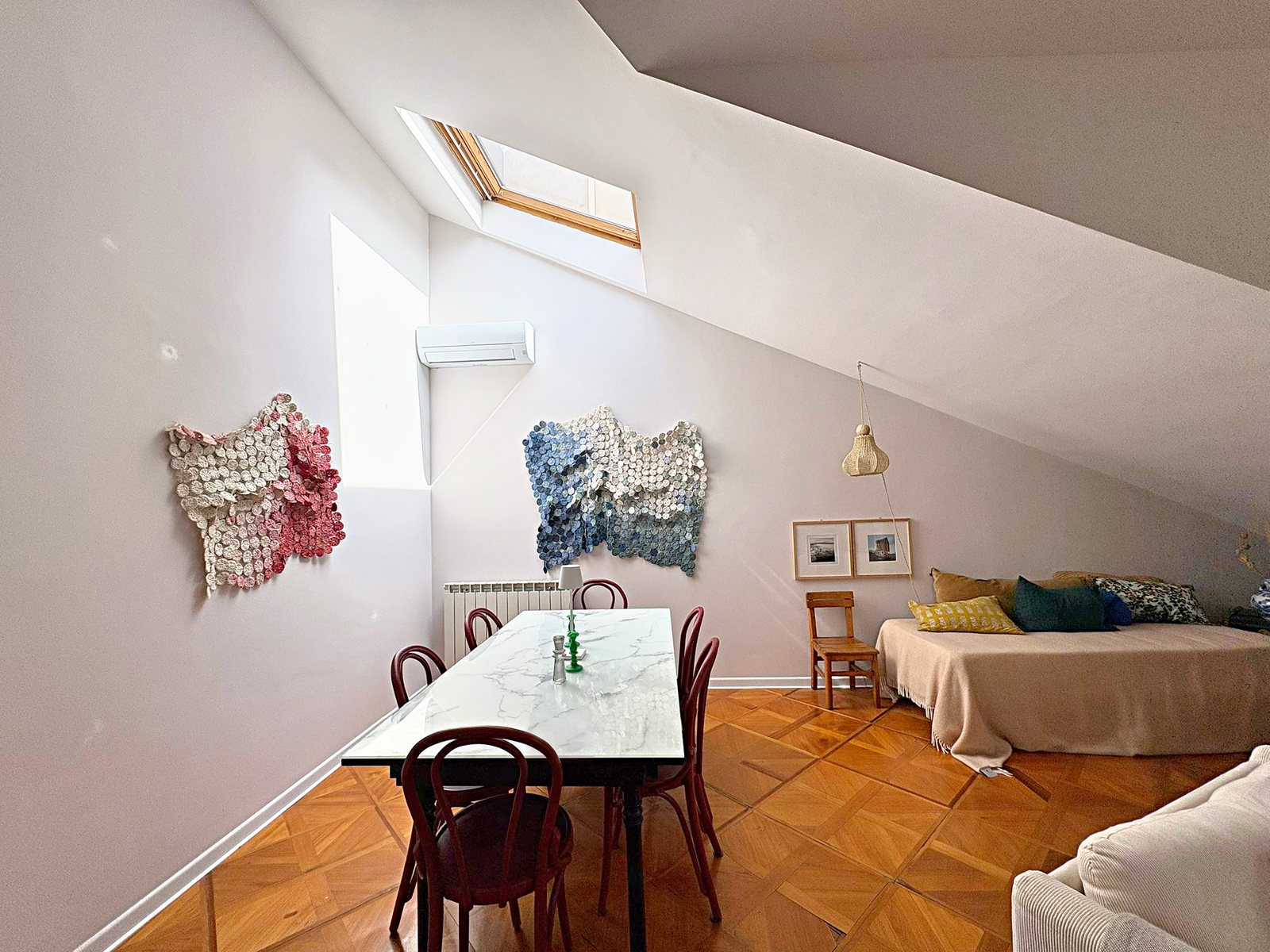 Zona pranzo mansardata con tavolo di marmo, sedie in legno curvato e lucernario, piazza Goldoni, Trieste