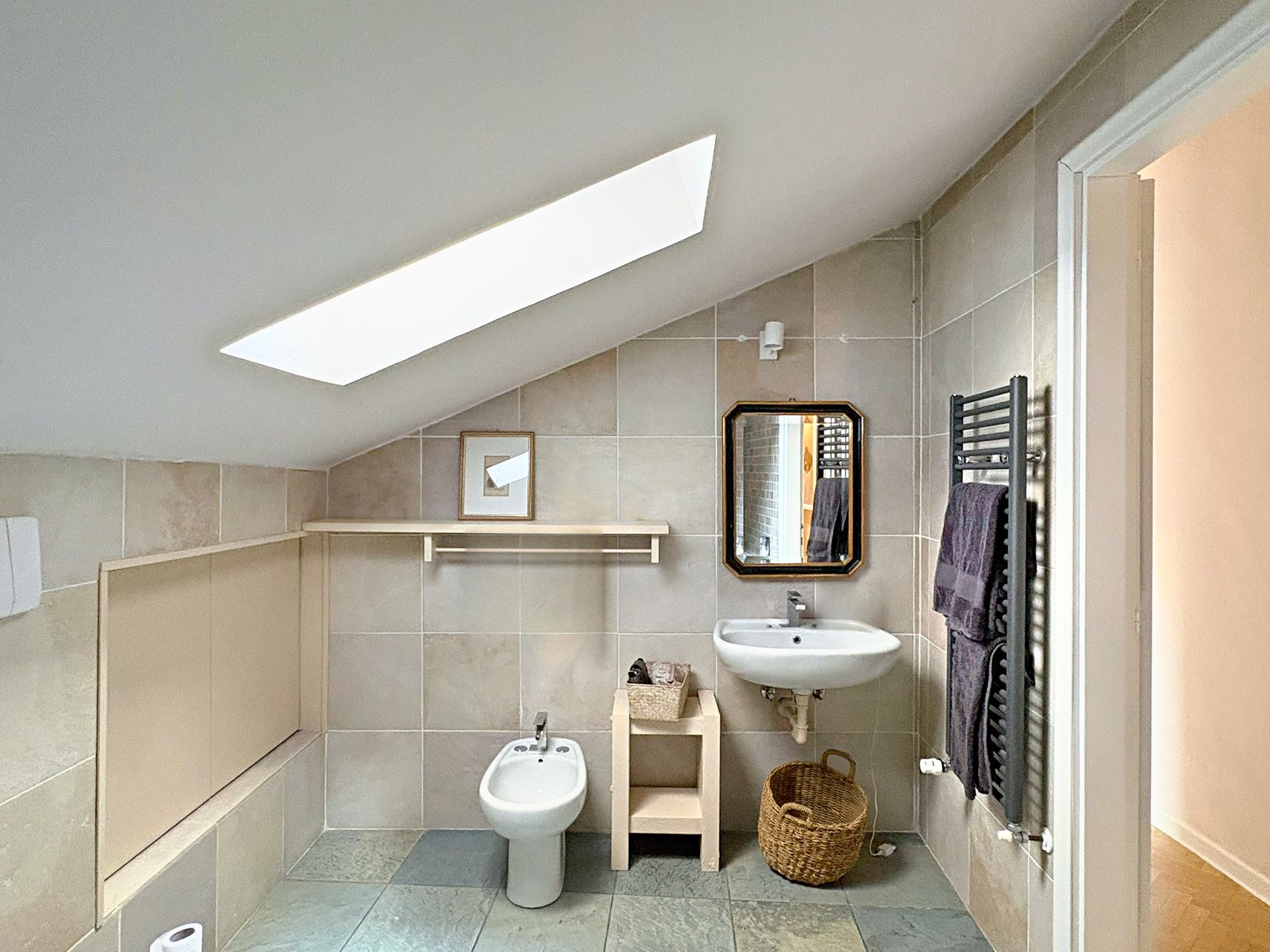 Bagno mansardato con lucernario, piastrelle in pietra, lavabo, bidet e scaldasalviette, piazza Goldoni, Trieste