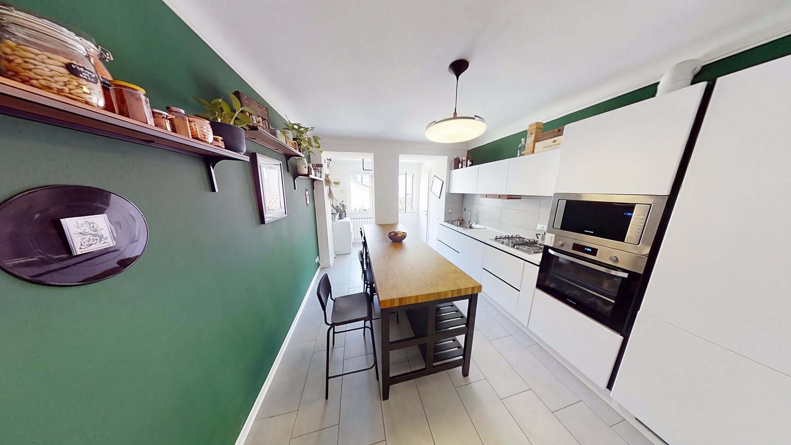 Kitchen with green wall, wooden island with stools, built-in oven and microwave, Via di Torre Bianca, Trieste