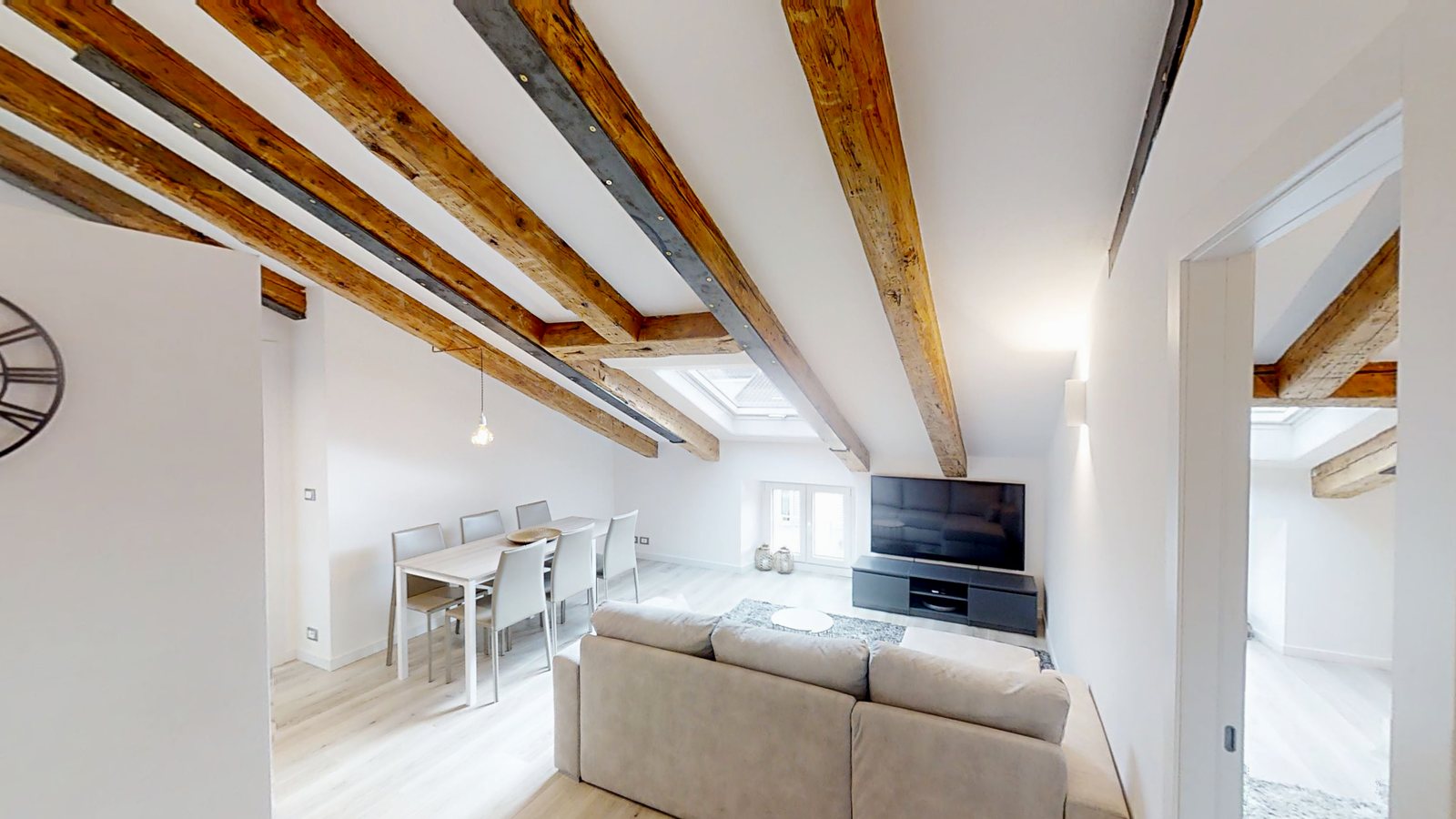 Attic living room with exposed timber beams, dining area and TV, Via Felice Venezian, Trieste
