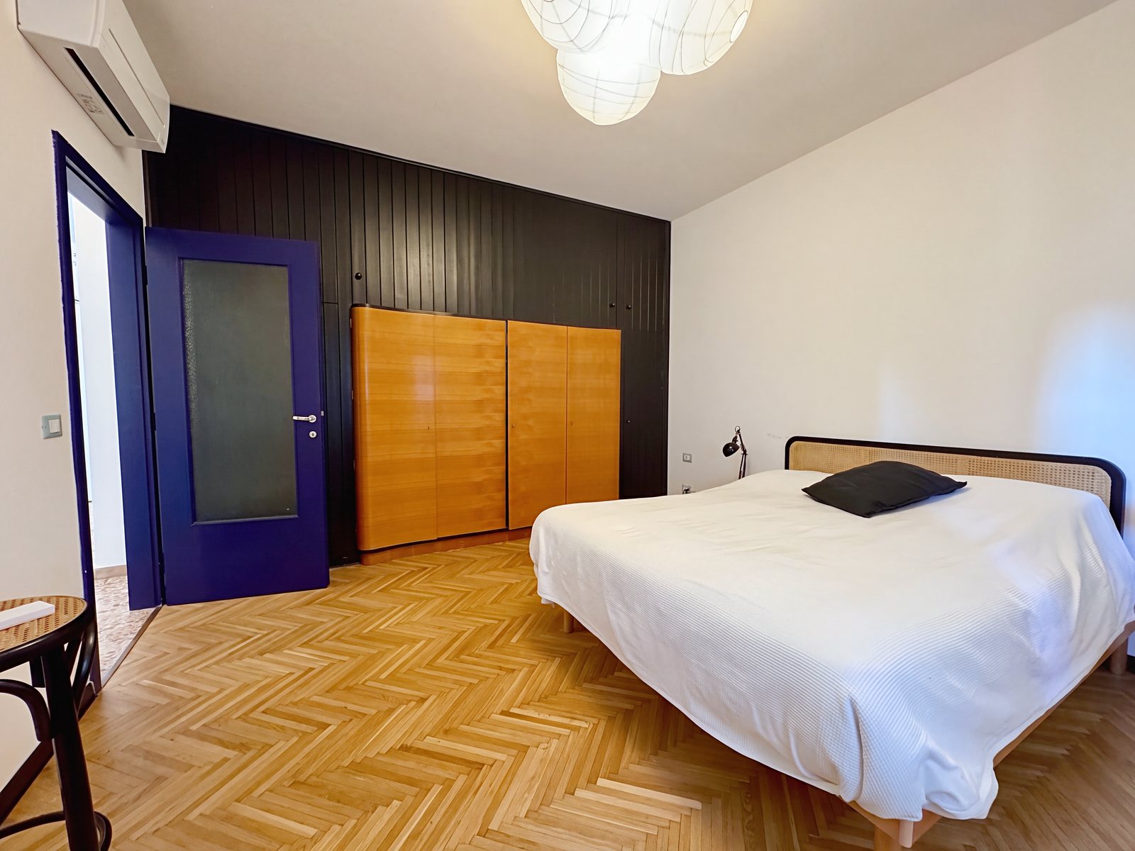 Spalnica z zakonsko posteljo, črno opaženo steno, leseno omaro in modrimi vrati, Via di Romagna, Trst