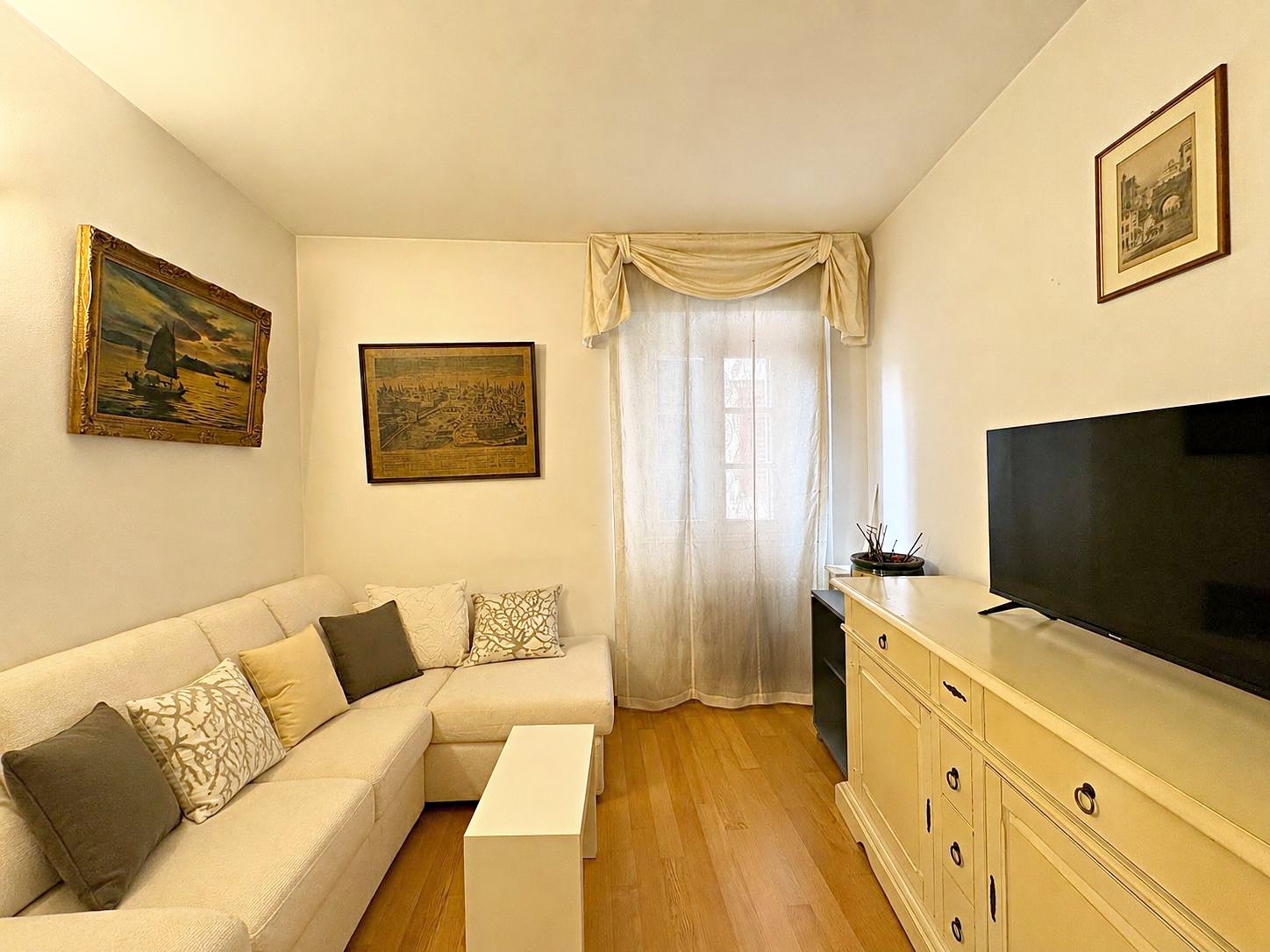 Soggiorno con divano angolare, mobile basso color crema e finestra con tenda, Via del Trionfo, Trieste