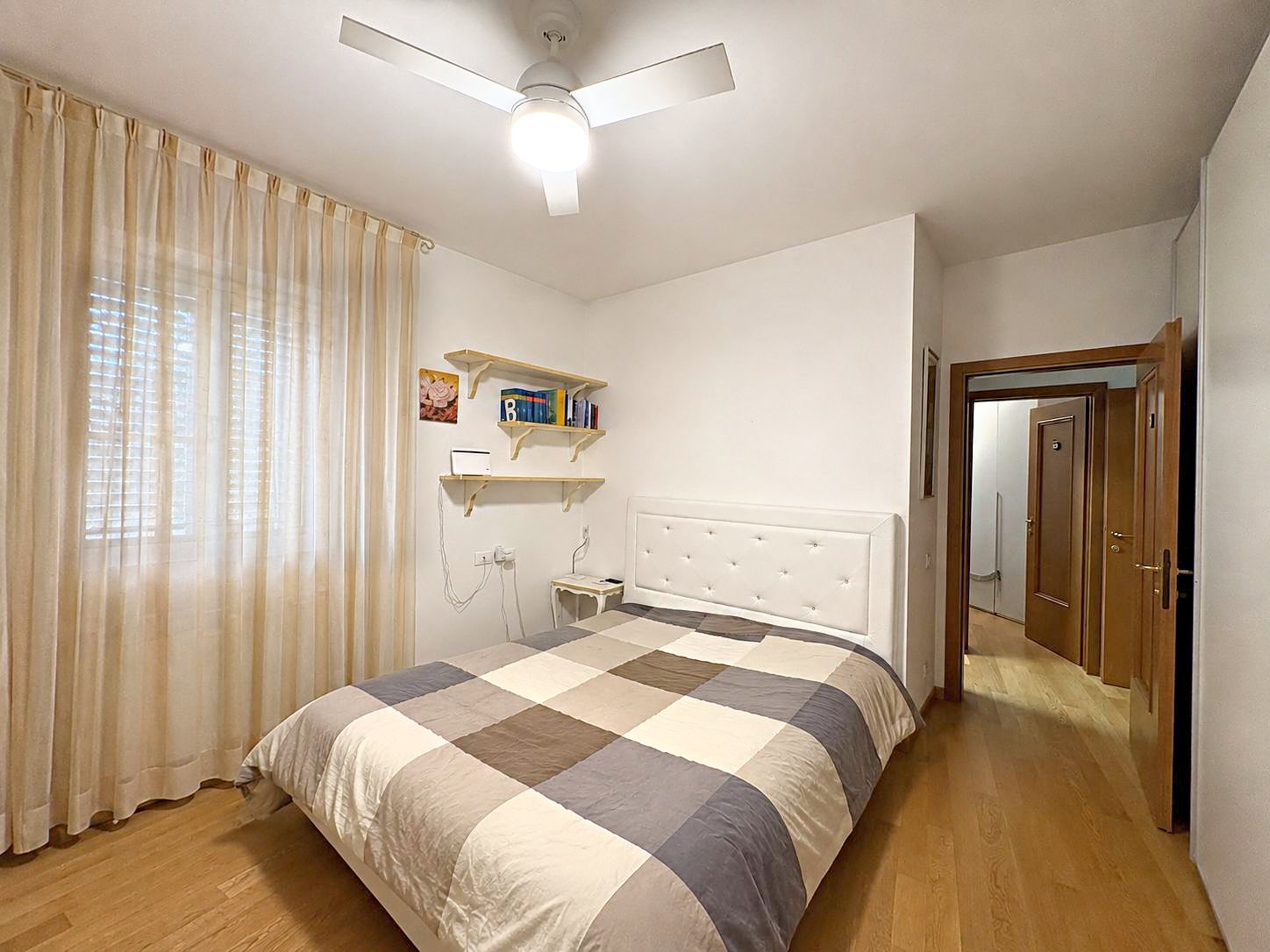 Camera con testiera imbottita, ventilatore a soffitto e mensole in legno, Via del Trionfo, Trieste