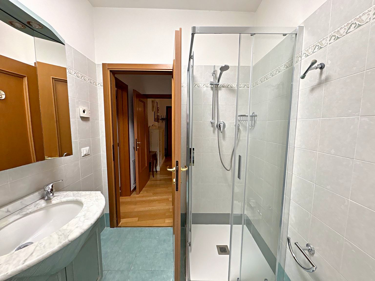 Bagno con box doccia in cristallo, lavabo con piano in marmo e piastrelle con listello, Via del Trionfo, Trieste