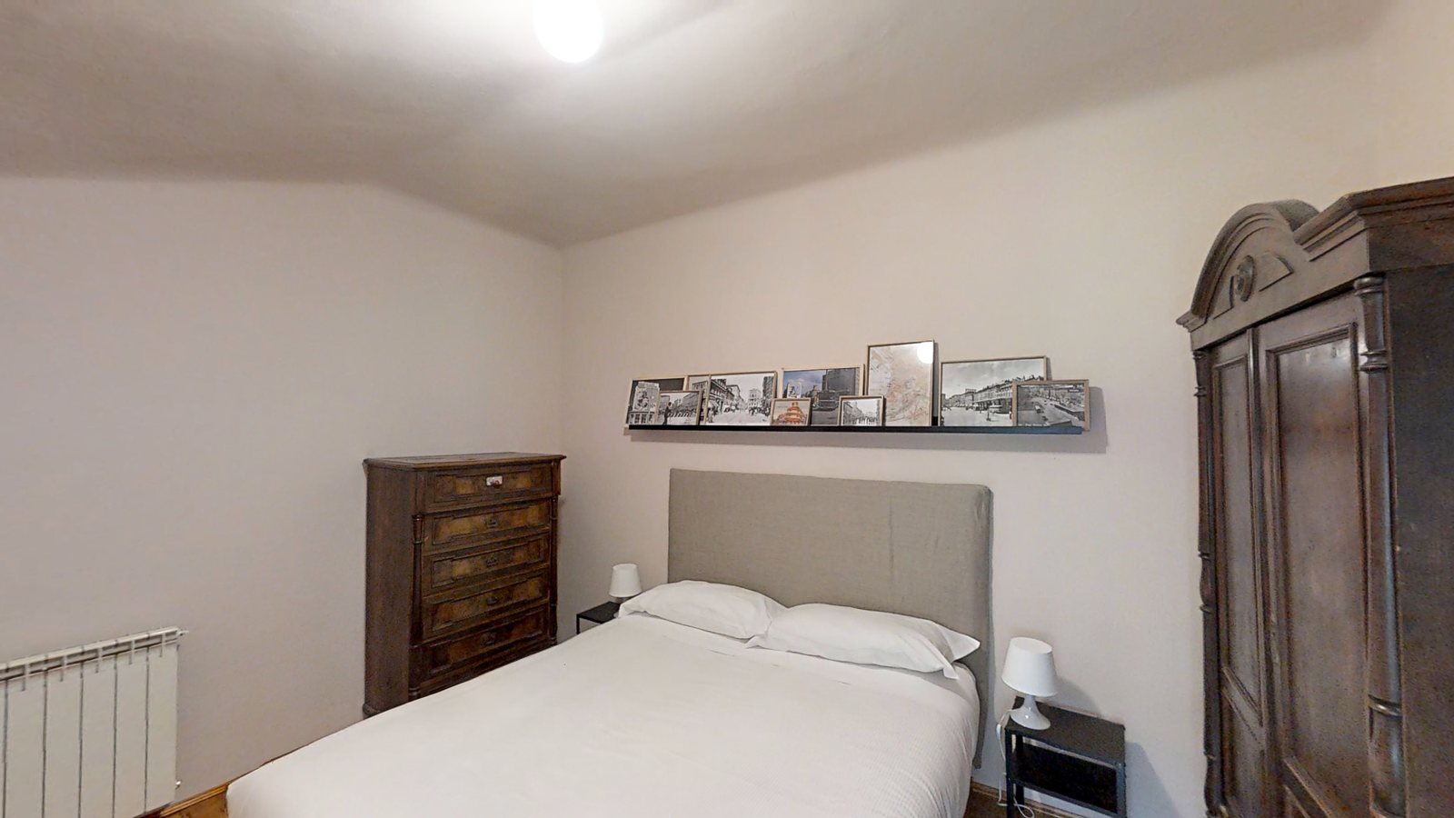 Schlafzimmer mit Doppelbett, antiker Kommode und Bildleiste mit alten Fotos, Via Corridoni, Triest