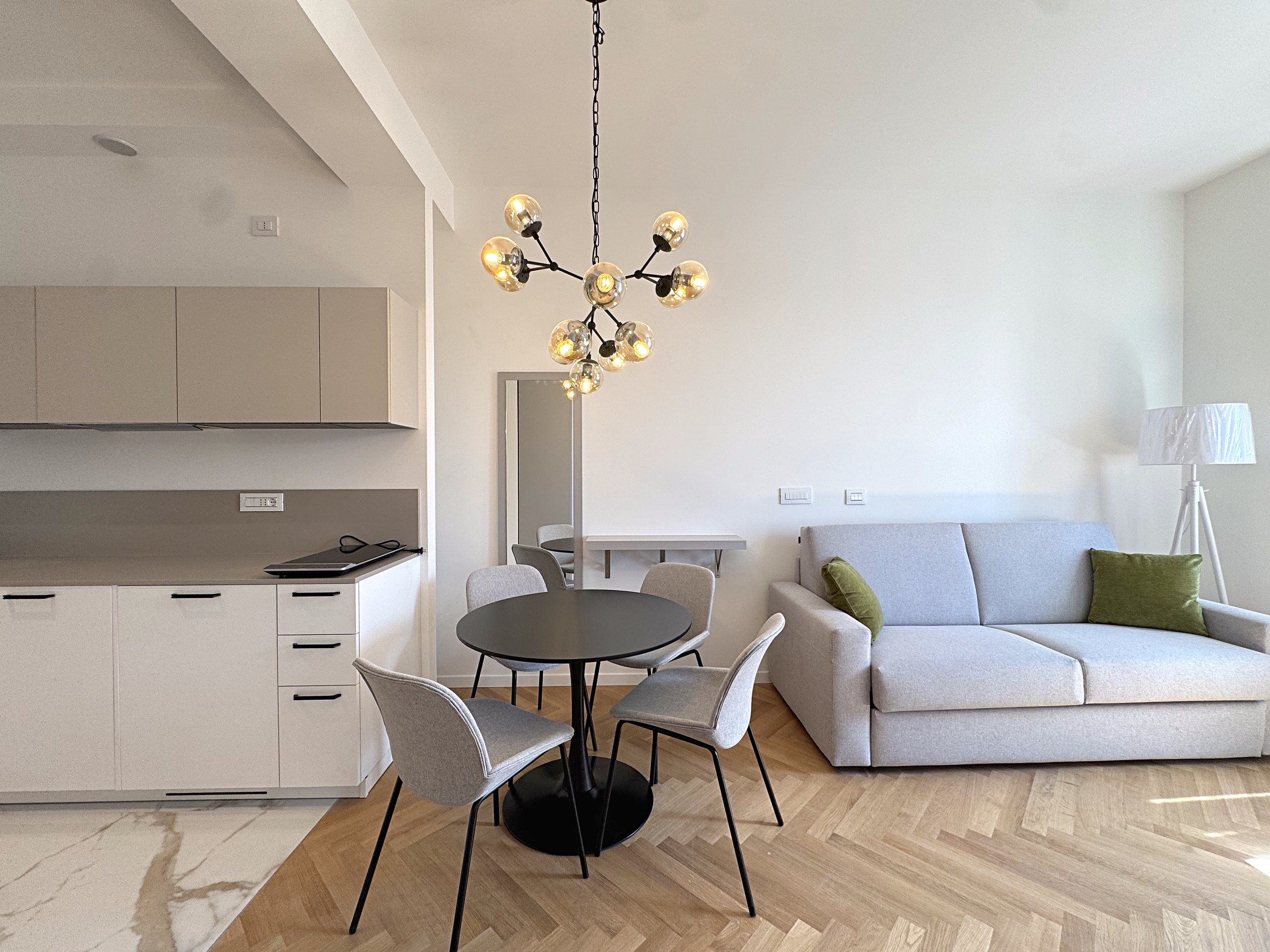 Fitted kitchen with white base units and induction hob, round table and sofa, Via Carducci, Trieste