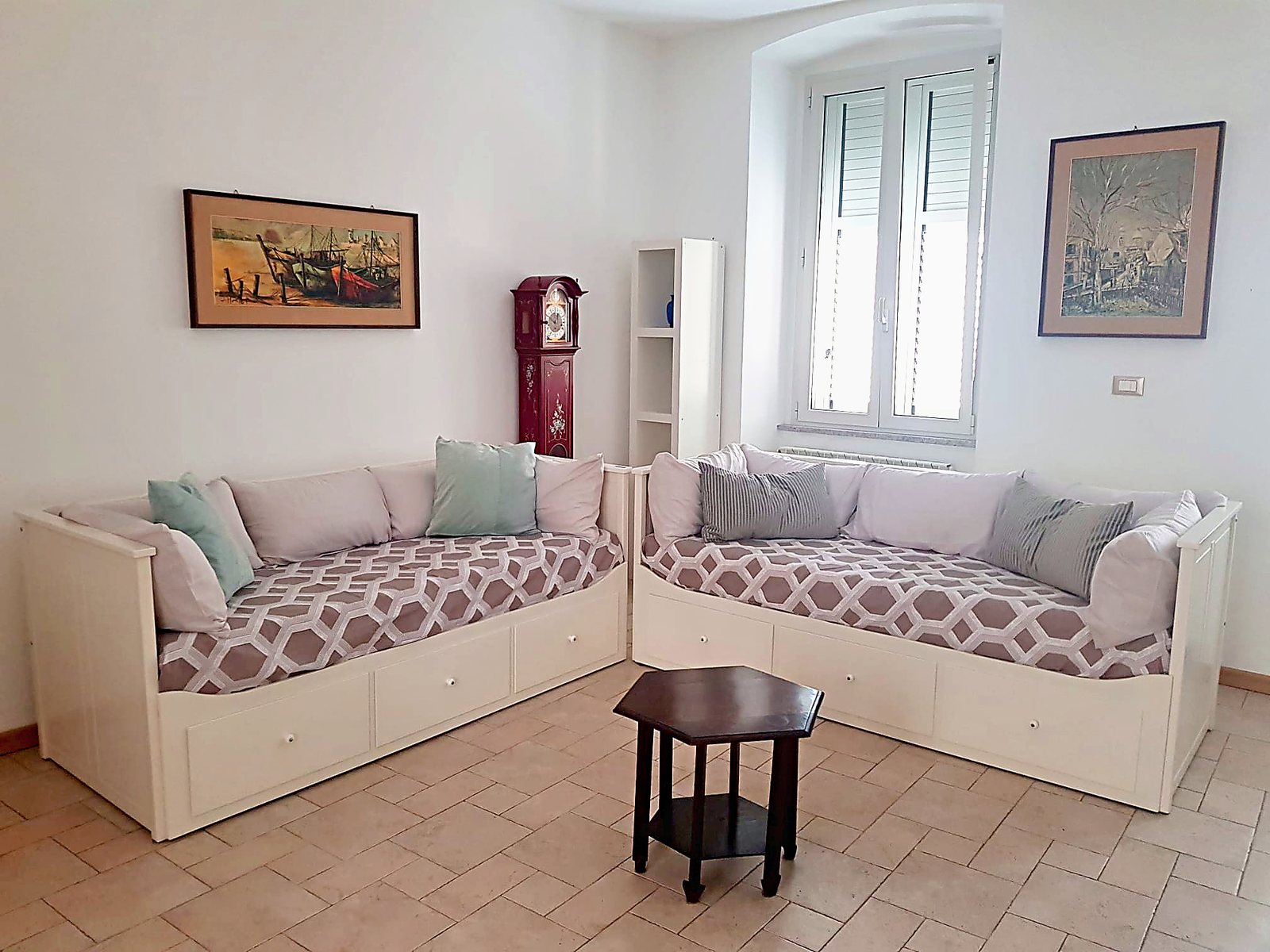 Wohnzimmer mit zwei Tagesbetten, bemalter Standuhr und Fenster, Via XXX Ottobre, Triest