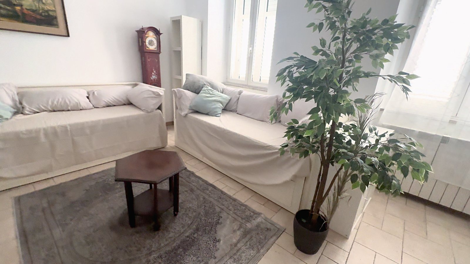 Soggiorno oggi: divani letto, tavolino esagonale, tappeto e pianta, Via XXX Ottobre, Trieste