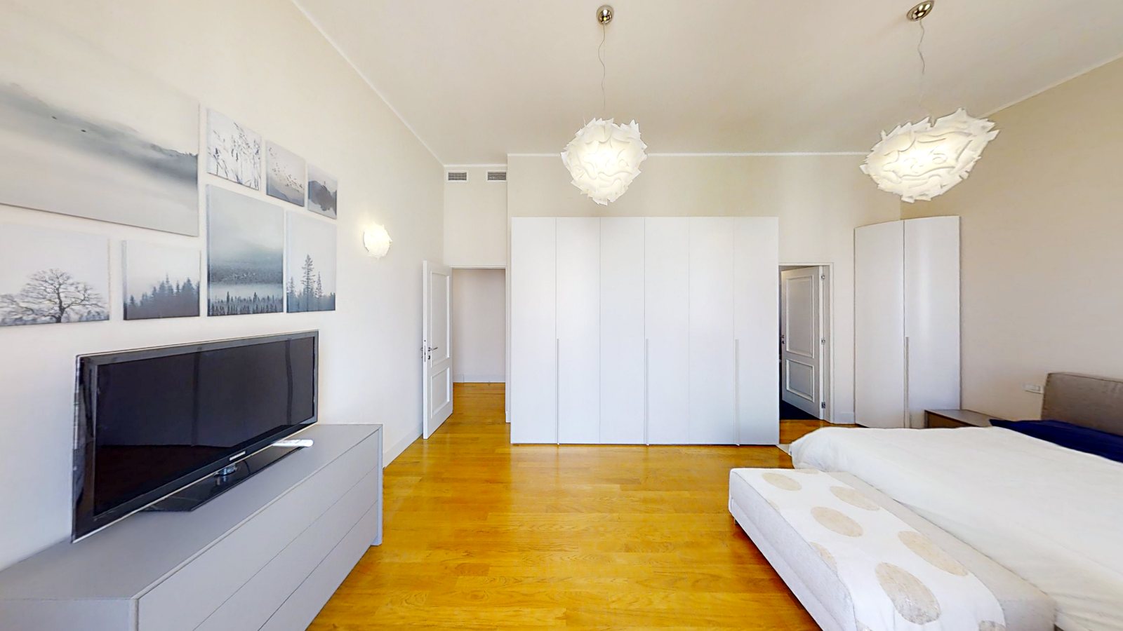 Doppelzimmer mit weißen Schränken, Fernseher und Landschaftsdrucken an der Wand, Palazzo Tergesteo, Triest